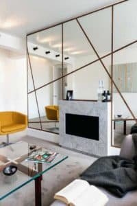 Sala de estar com lareira e espelho de parede inteira moderno com mesa de centro de vidro