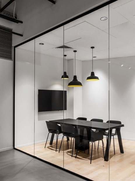 escritorio com chao de madeira e divisorias de vidro com acabamento em preto