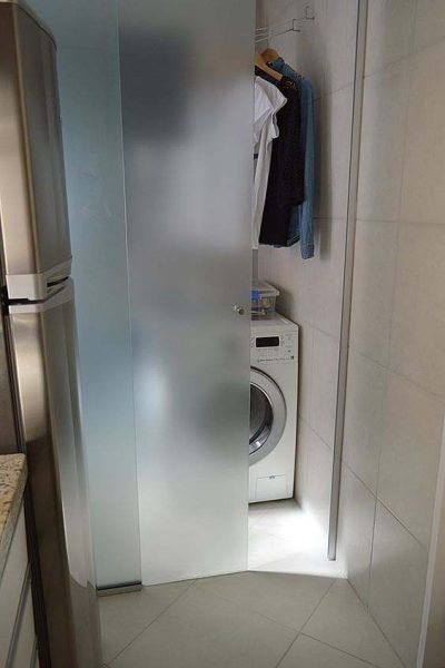 Porta de vidro dividindo área de serviço e cozinha.